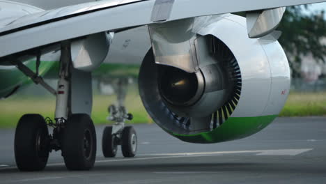 close-up view of aircraft engine and landing gear on runway, highlighting turbine design and green accents, emphasizing aviation technology