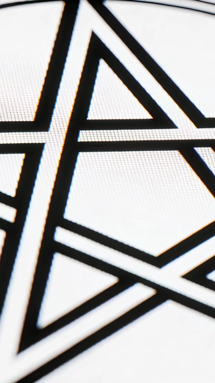Video verticale: Telecamera in movimento che rivela un motivo geometrico nero su un piano d'appoggio bianco, mostrando la grana.