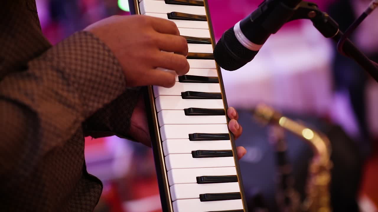 Hands of musician playing on melodica in concert. Gimbal, shallow focus