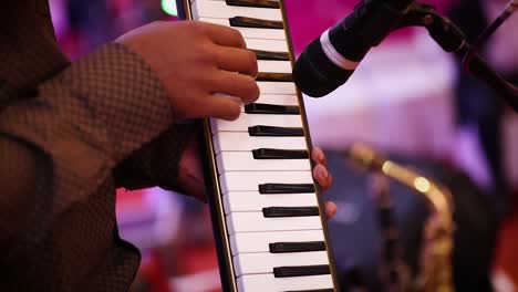 hands of musician playing on melodica in concert. gimbal, shallow focus