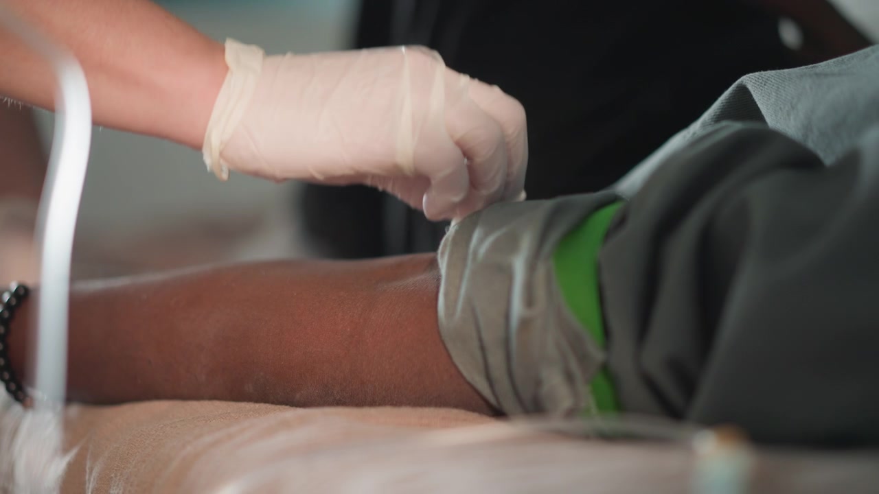 Prelievo di sangue a domicilio. Infermiera esperta guida l'ago nella vena con precisione e sicurezza. Operatore sanitario professionale esegue il prelievo di sangue sterile in condizioni di assistenza domiciliare