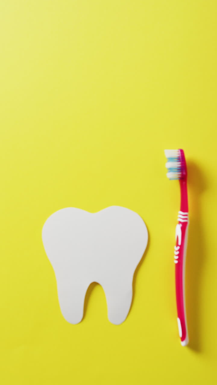 video vertical de la forma del diente y el cepillo de dientes rojo sobre fondo amarillo, con espacio para copiar