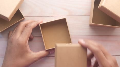 hands holding a cardboard box on a wooden table