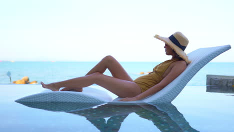 A-fit-asian-woman-lying-on-bed-in-infinity-pool-and-enjoying-the-view-on-sea-horizon