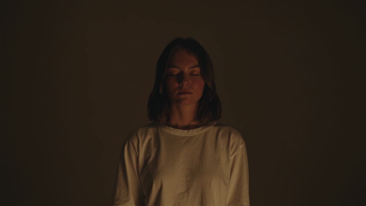 Mujer posando con camisa blanca, cerrando los ojos mientras las luces del estudio se intensifican para la revelación de un retrato.