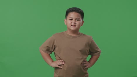 an asian boy warmly smiling on green screen background in the studio