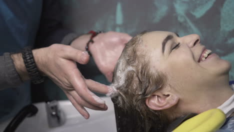 young woman with hairdresser cutting hair at salon