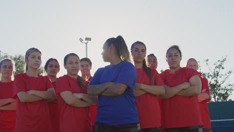 portrait of determined female soccer team with coach on training ground against flaring sun