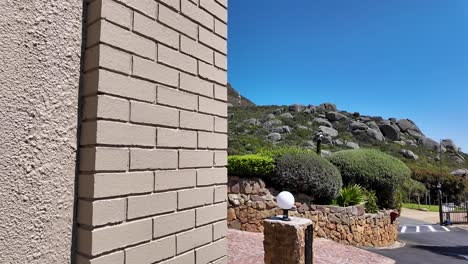 a reveal of lion's head framed by a brick building and rock wall, cape town, south africa.