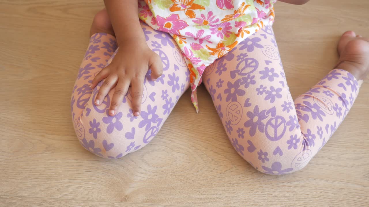 niña pequeña con leggings rosados con signos de paz y flores