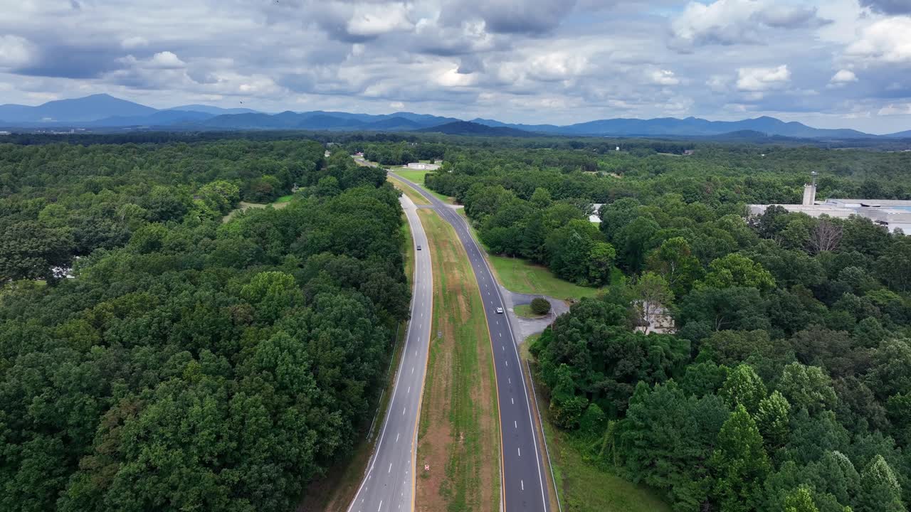 Driving vehicles on America. Highway between forest trees and hills of blue ridge Mountains in Virginia, USA. Ascend drone wide shot. Cloudy summer day on afternoon