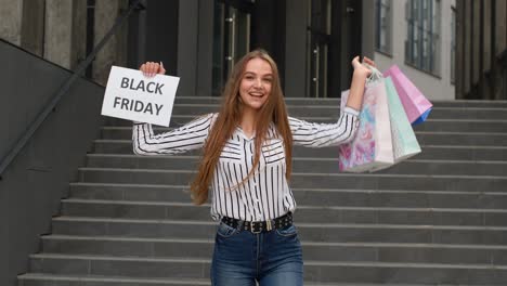 joyful teen girl showing black friday inscription, smiling, looking satisfied with low prices