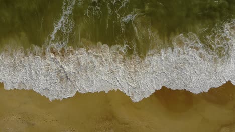 Top-View-of-the-Ocean-Shore-With-Waves-Crashing-on-the-Sandy-Beach