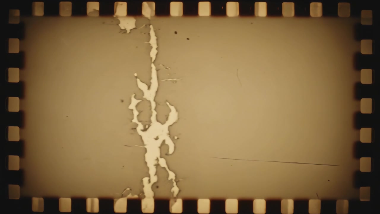 Mostra una pellicola da 35mm che si muove nel gate di uno scanner, rivelando un'emulsione scrostata e in movimento vicino alle perforazioni