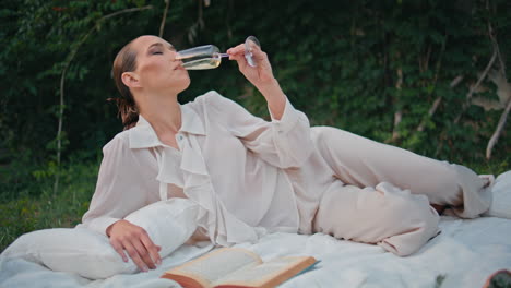 picnic woman drinking wine on blanket at green garden. lady enjoy champagne
