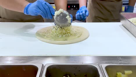 el queso se está extendiendo sobre la masa de pizza por los cocineros