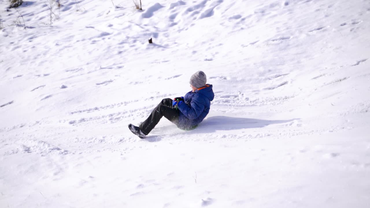 Child boy having fun, riding from a hill. Frost winter season.Cute little boy with saucer sleds outdoors on winter day and hits his friend or sister or brother, ride down the hills, winter games and fun. Two children hit while sledging.