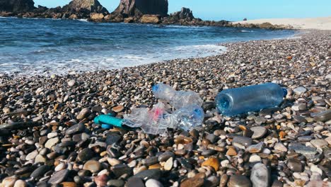 plastic bottles and trash washed onto a rocky beach, highlighting coastal pollution