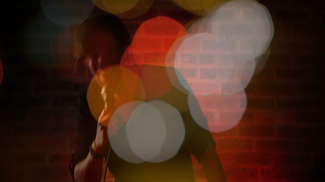 man gripping microphone performing in entertainment, featuring warm red light and bokeh graphics