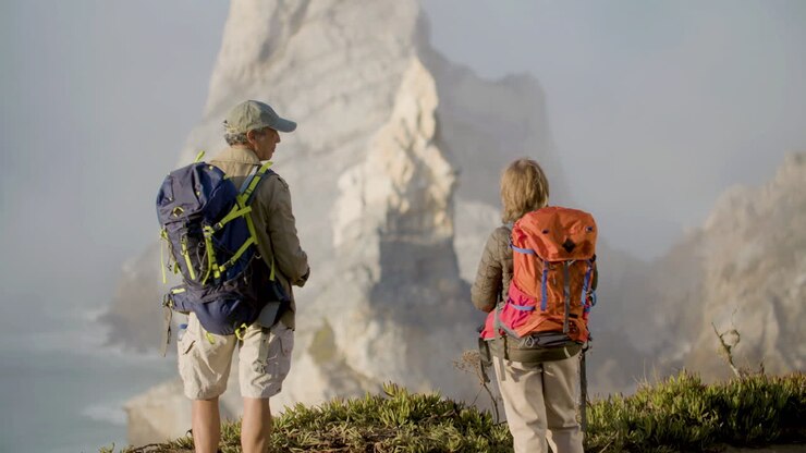 Back view of senior hikers holding hands and kissing while admiring the gorgeous landscape