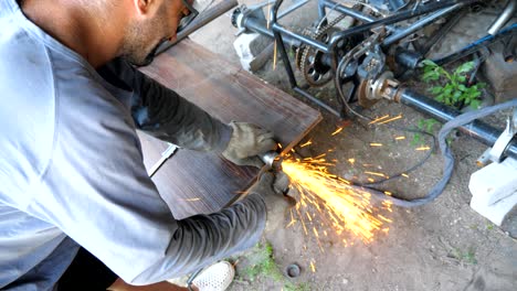 adult repairman or mechanic grinding metal using circular saw. worker cutting some detail in garage or workshop. man sawing iron part with electric grinding wheel. slow motion close up dolly shot