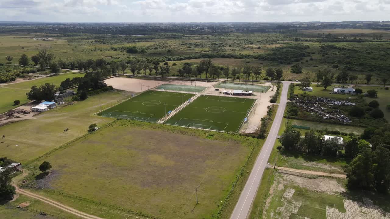 Construction progress of soccer fields emerging in rural landscape, aerial perspective revealing green terrain transformation and infrastructure development