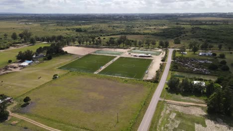 construction progress of soccer fields emerging in rural landscape, aerial perspective revealing green terrain transformation and infrastructure development