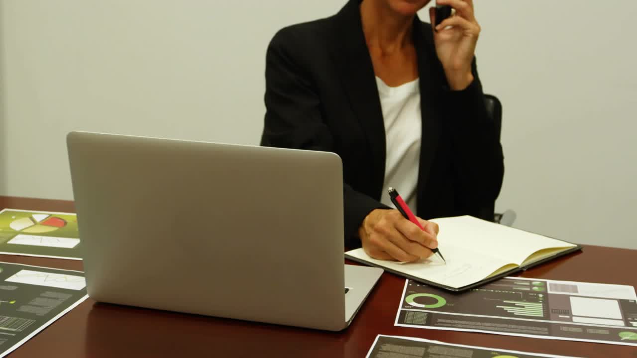 Un administrador baja el teléfono, empieza a tomar notas y comprueba el teléfono en una reunión de negocios, iconos de interfaz superpuestos