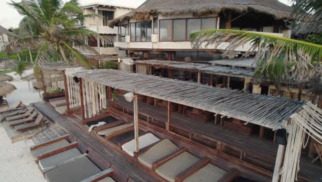 aerial drone view zooming in to a vacation home on the beach with chairs on the sand