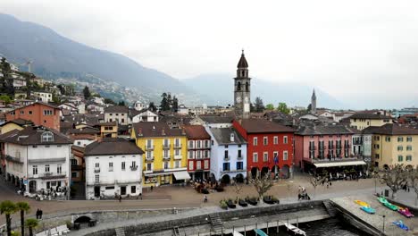 Vista-Aérea-De-Ascona-En-Ticino,-Suiza-Con-Vistas-Al-Paseo-Junto-Al-Lago-A-Orillas-Del-Lago-Maggiore,-Rodeado-De-Coloridas-Casas-Y-Barcos