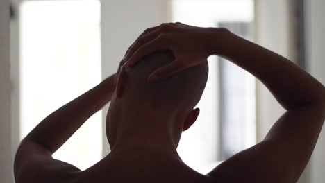 black woman touching head at home