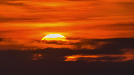 view of sun setting in the yellow sky with dark clouds in timelapse