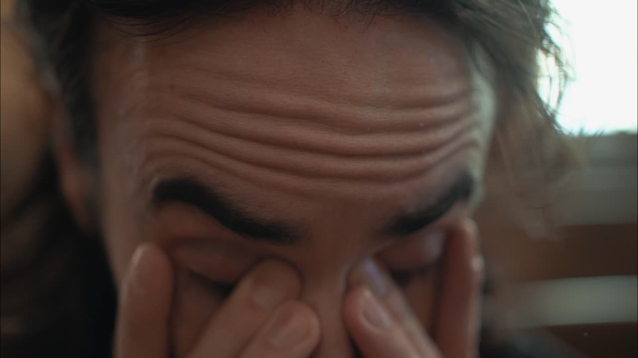 스트레스를 받고 슬픈 남자가 감정적 고통 속에서 얼굴을 문지르고