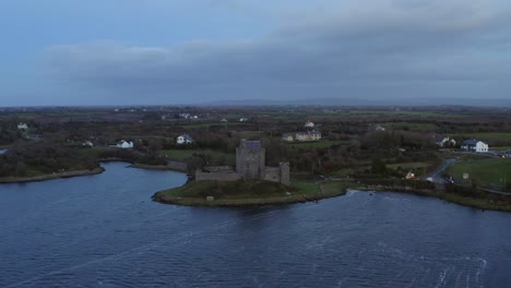 Aerial-pullback-showcasing-Dunguaire-Castle-against-a-twilight-scene-with-a-serene-blue-sky