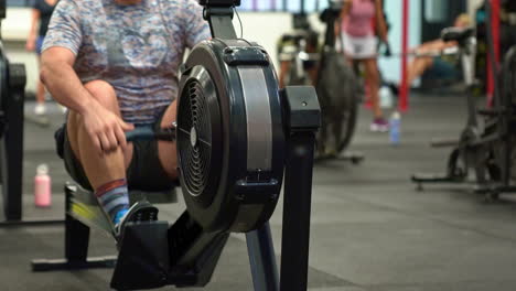 atleta masculino en máquina de remo en un gimnasio ocupado