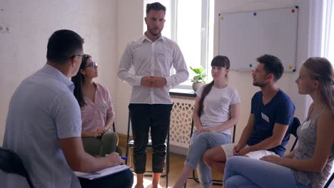 sesión de terapia, hombre hablando de problemas psicológicos y compartiendo emociones de pie frente a la gente