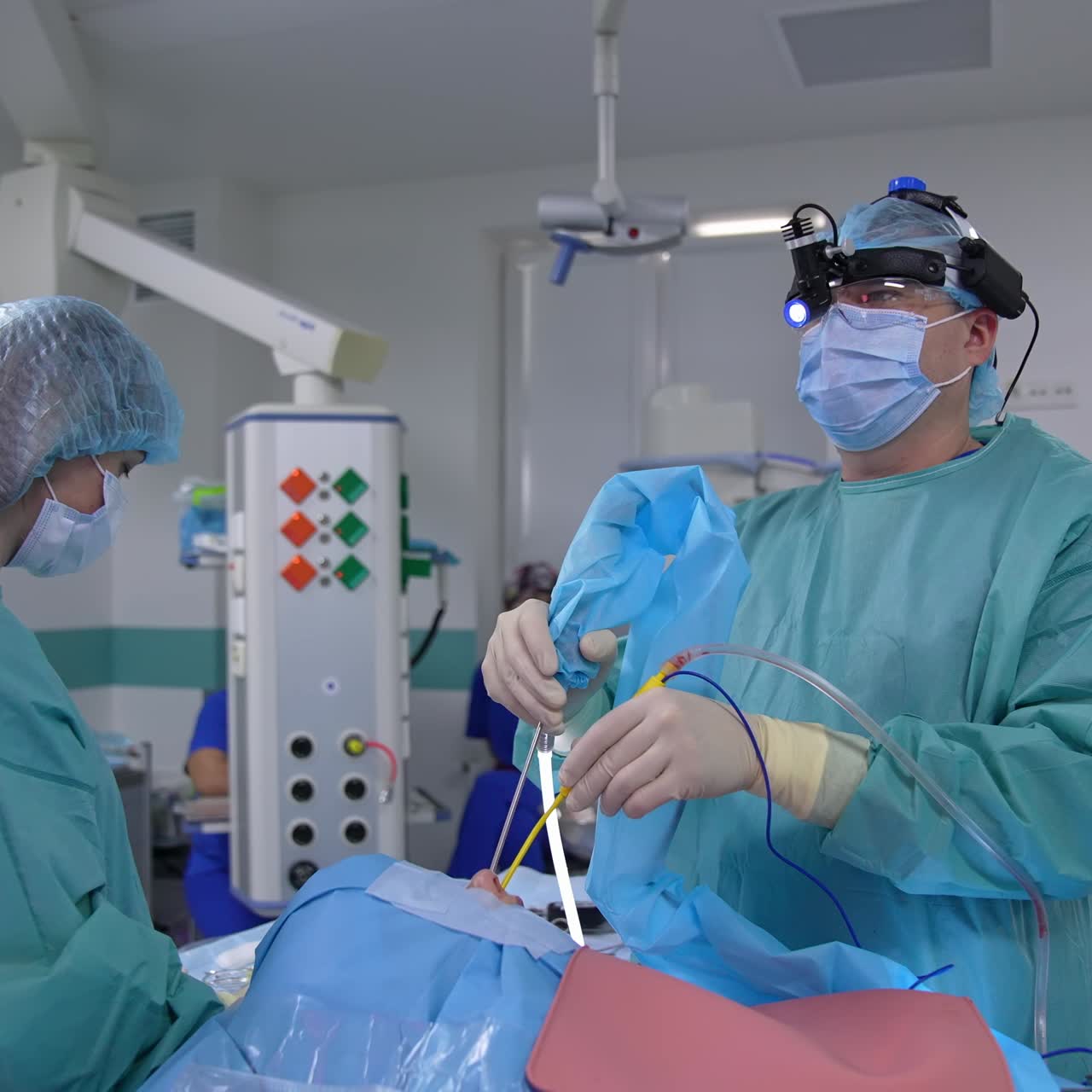 Cirujano operando con equipo especial en la cabeza en la sala de operaciones. El médico observa la operación en la pantalla. El cirujano aplica herramientas médicas al paciente.