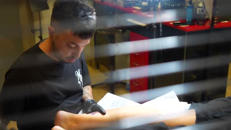tattoo artist concentrating while working on intricate leg tattoo for client at studio