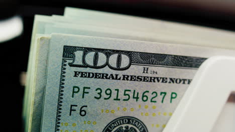 close-up of hundred dollar bills in a cash handling machine