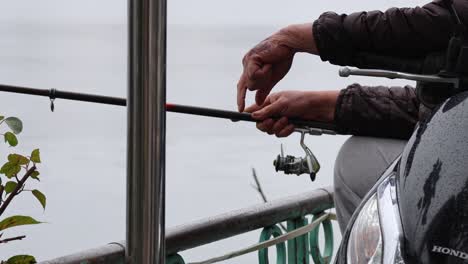 man fishing with rod near river railing