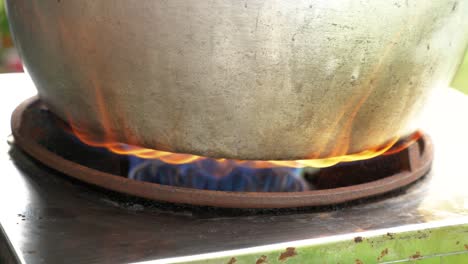 stainless steel pot on burning flame boiling water, close up handheld view