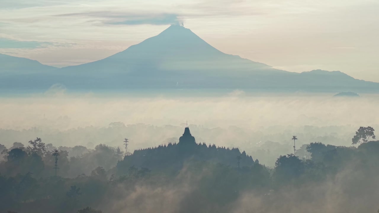 Alba nebbiosa sul Tempio di Borobudur con un maestoso sfondo montuoso, creando un paesaggio sereno e suggestivo in Indonesia. Perfetto per temi di viaggio e natura