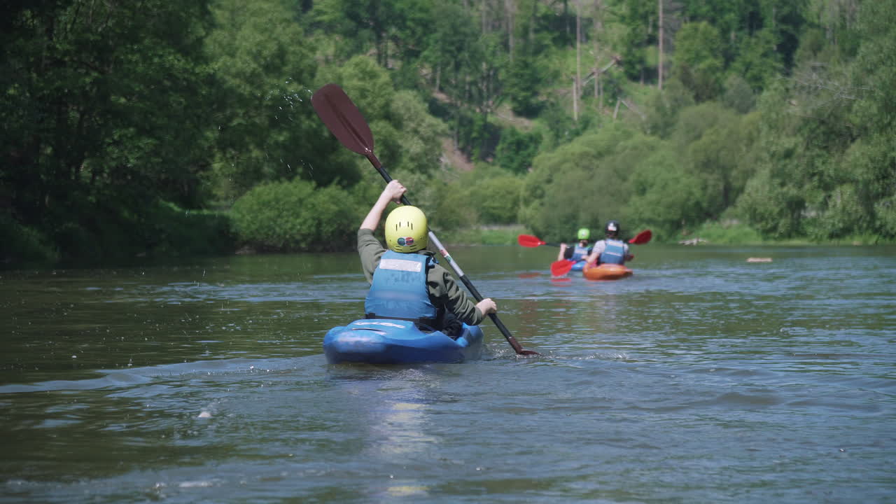 Kayaker kayaking Sazava river with group of kayakers in background, Sazava river, Czech Republic, back view