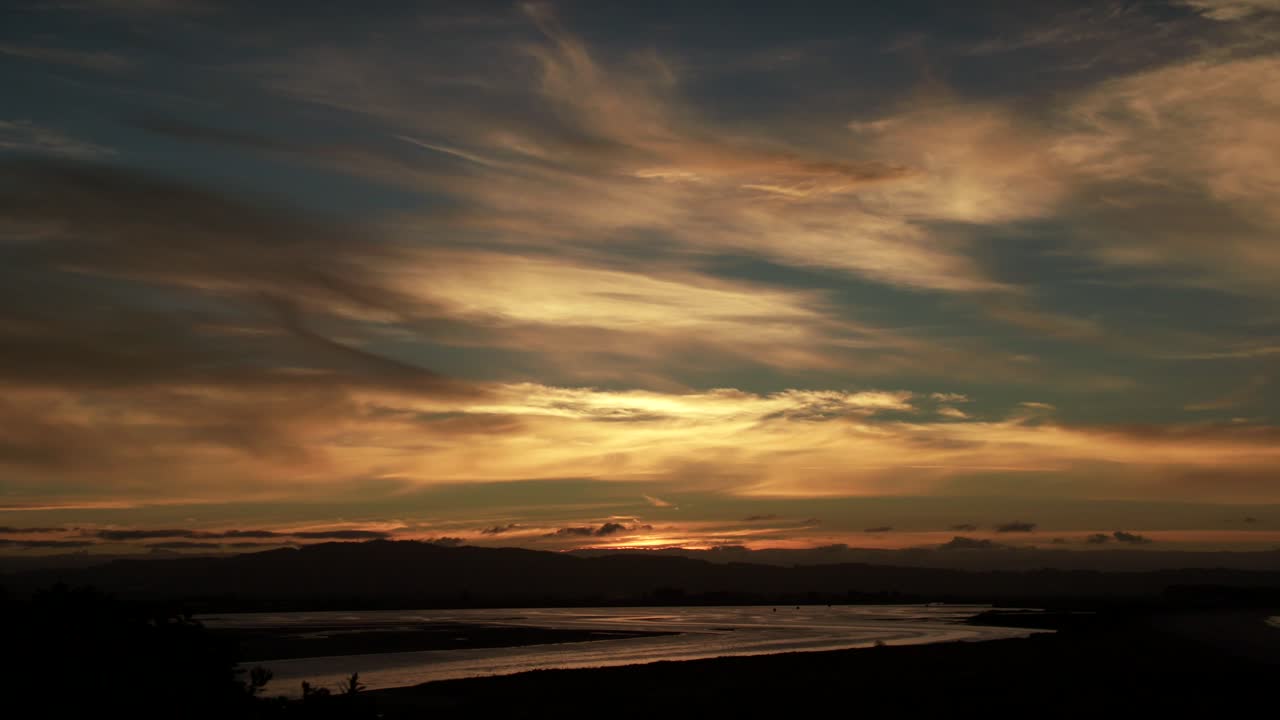Stunning peaceful Whakatane golden sunset with illuminated clouds, pan down
