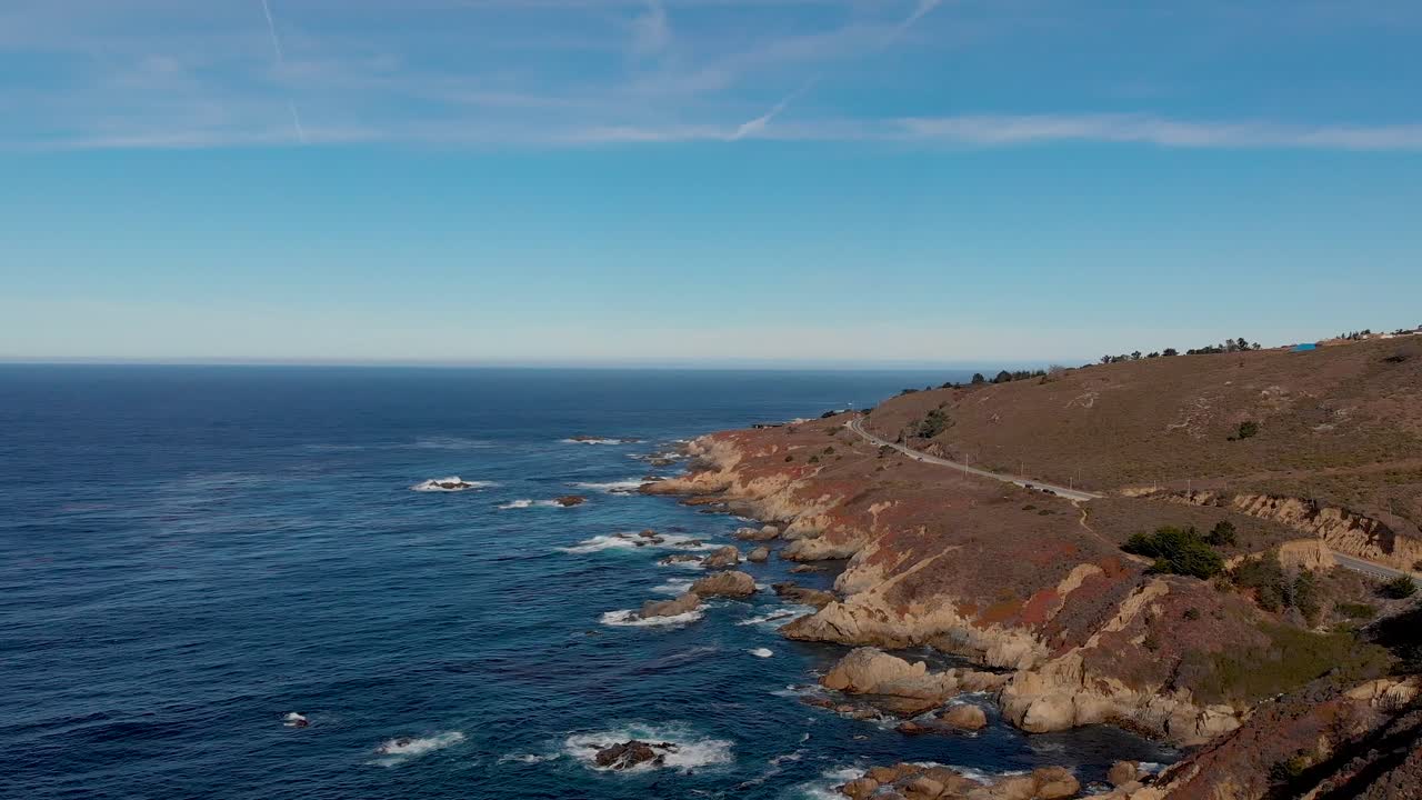 북부 캘리포니아의 바위가 많은 해안 근처의 햇살 가득한 해안 고속도로를 달리는 자동차