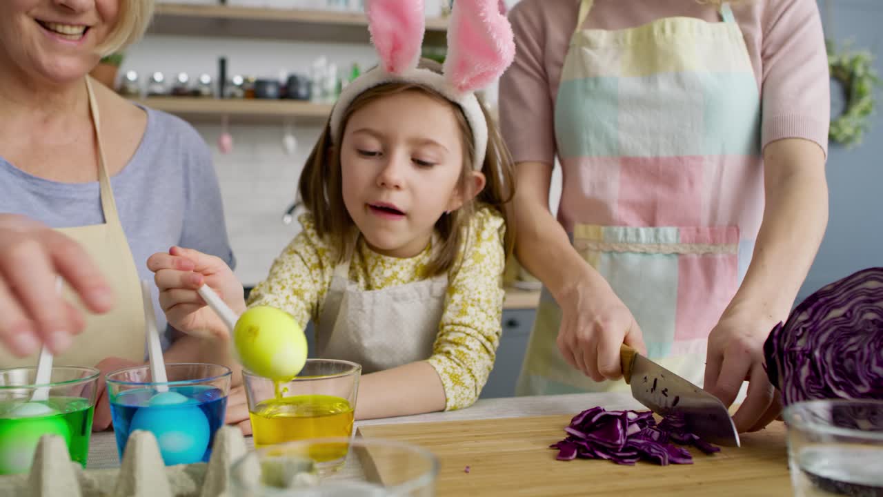 Tracking video of girl with grandmother taking out dyed eggs