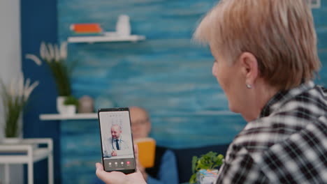 middle aged woman talking at video conference calling with remote doctor