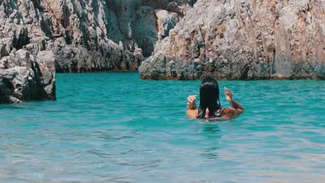 girl splashing hair in the turquoise waters, inside a canyon