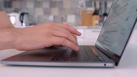 persona escribiendo en una computadora portátil en la cocina