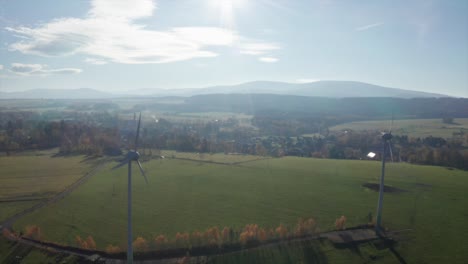 Windkraftanlagen-An-Einem-Sonnigen-Tag-In-Der-Nähe-Des-Dorfes,-Umgeben-Von-Einer-Wiese